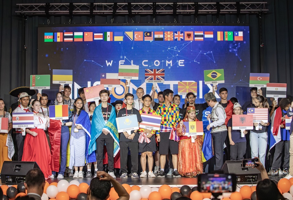 Students from partner countries on stage at the Infomatrix opening ceremony, holding up their national flags.